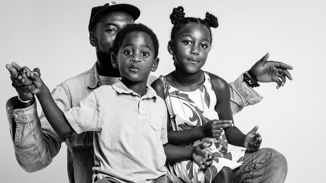 Black and white studio portrait of a father with his young son and daughter playing