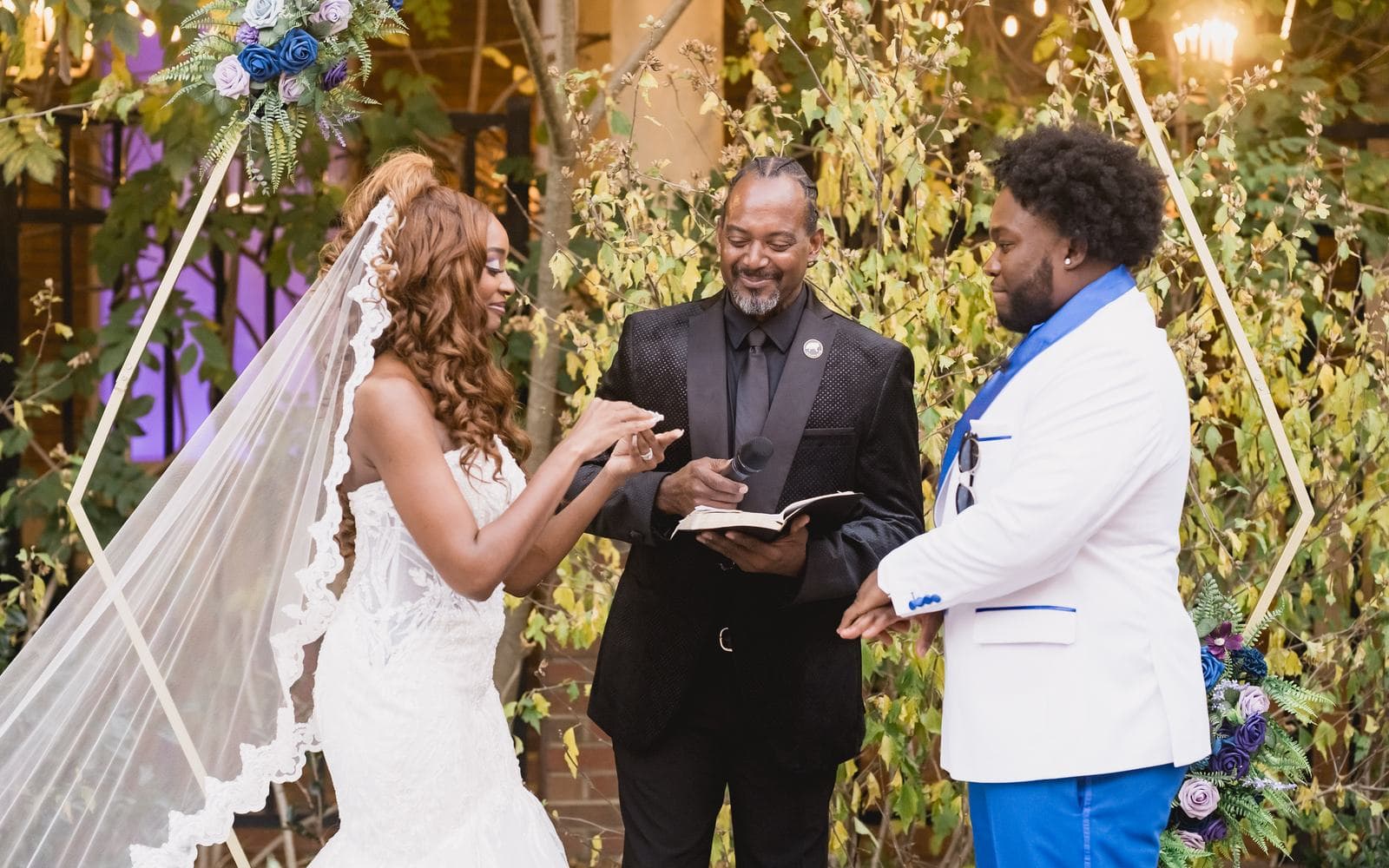 Bride and groom exchanging vows under a floral arch