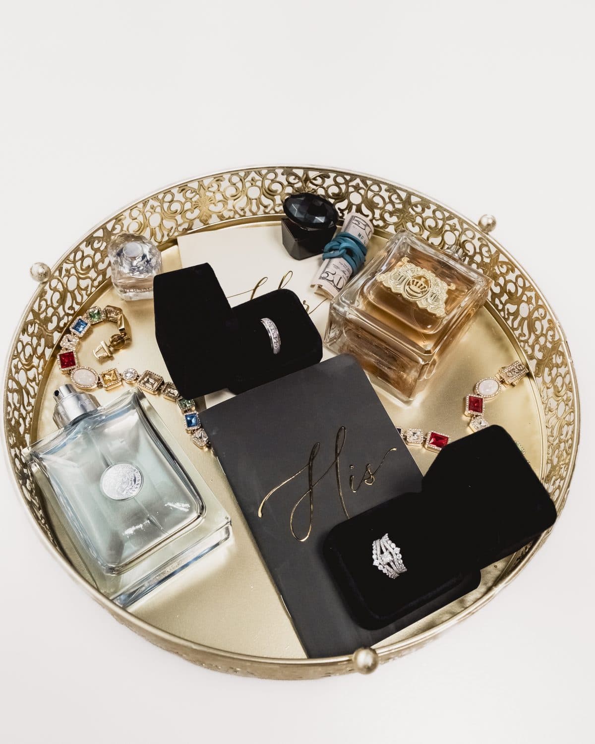 Wedding rings, perfume and accessories arranged on a gold tray