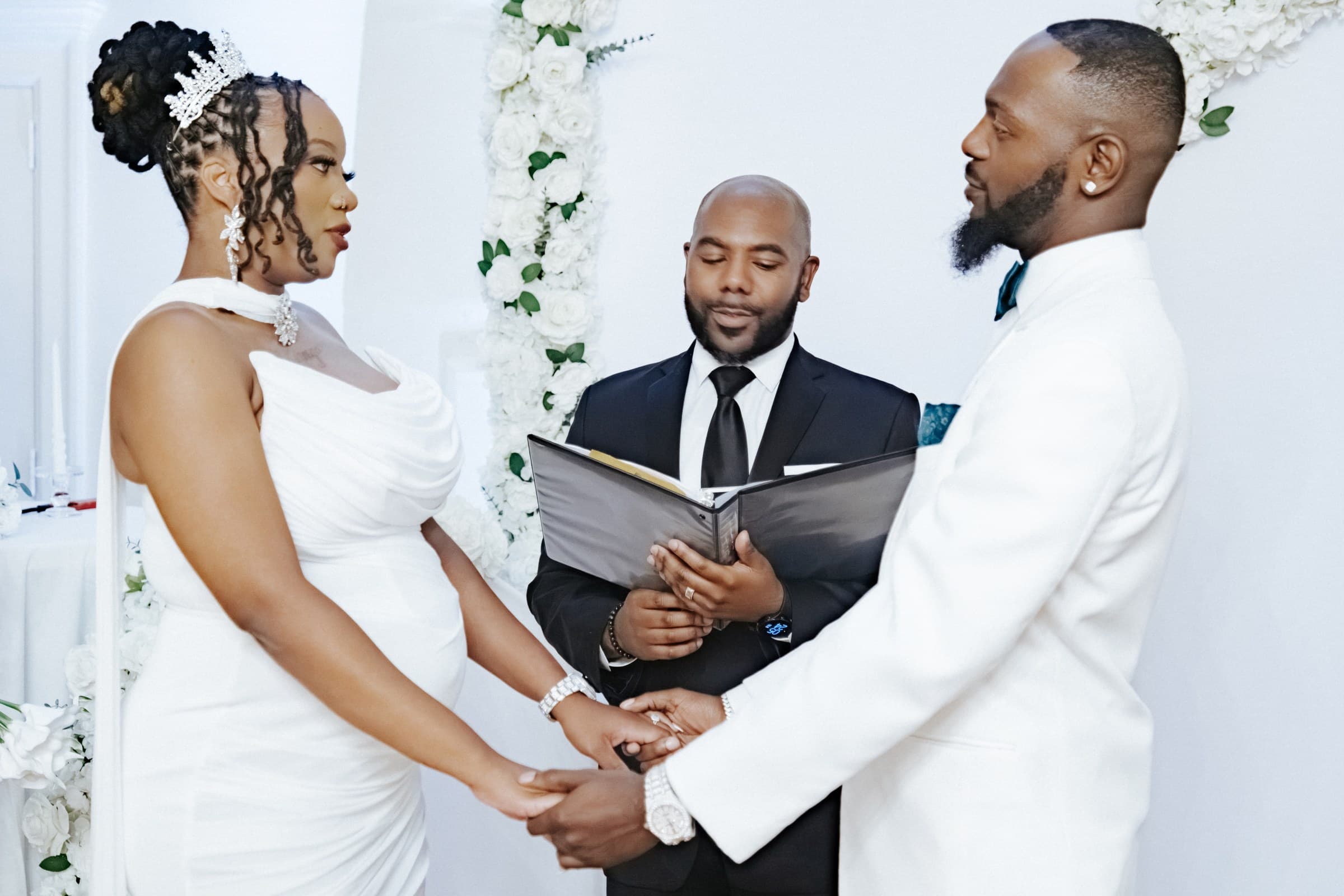 Bride and groom holding hands as the officiant reads during their ceremony