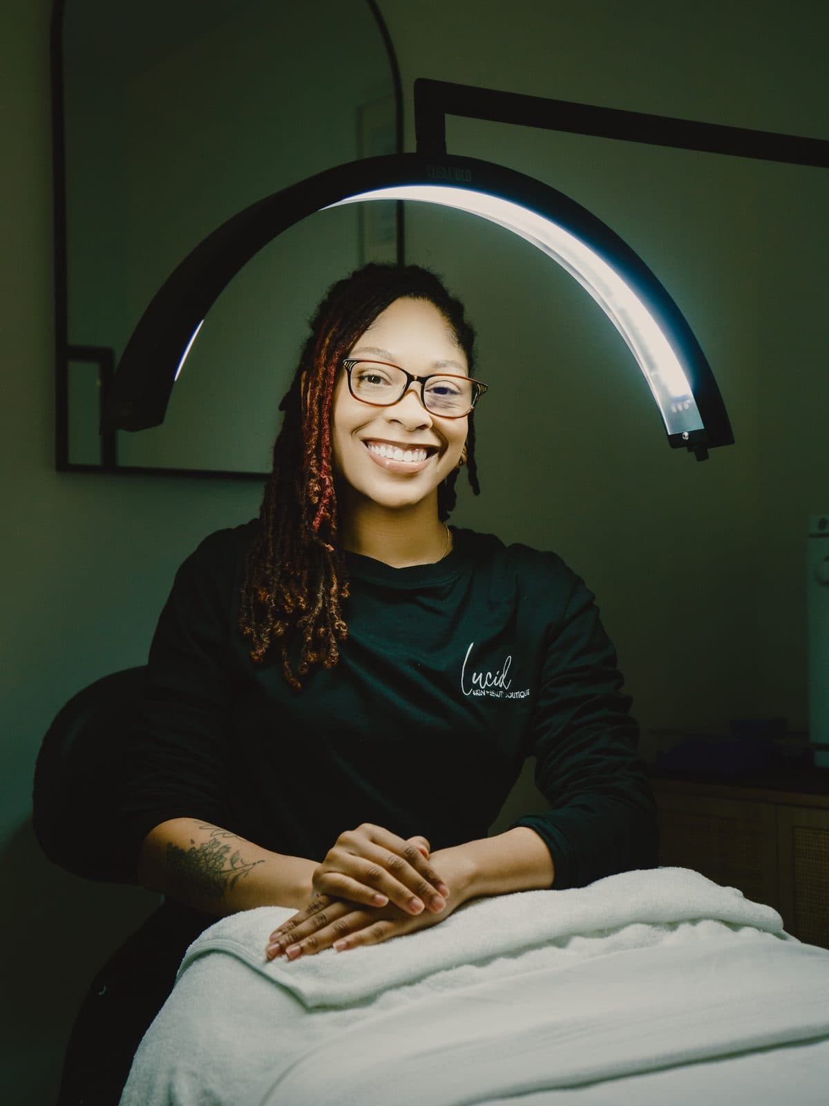 Smiling esthetician seated in her studio
