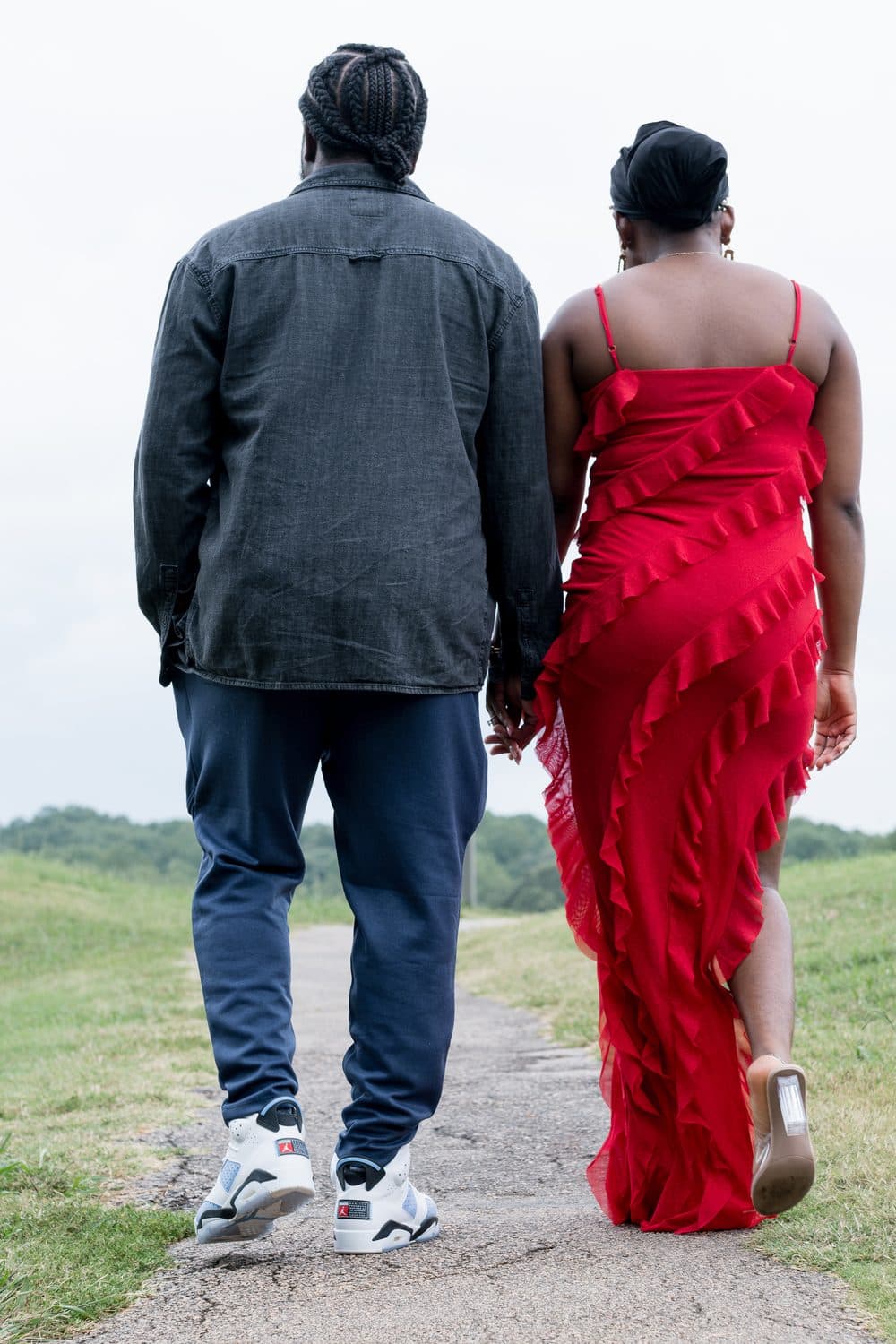 Couple walking hand in hand along a grassy path