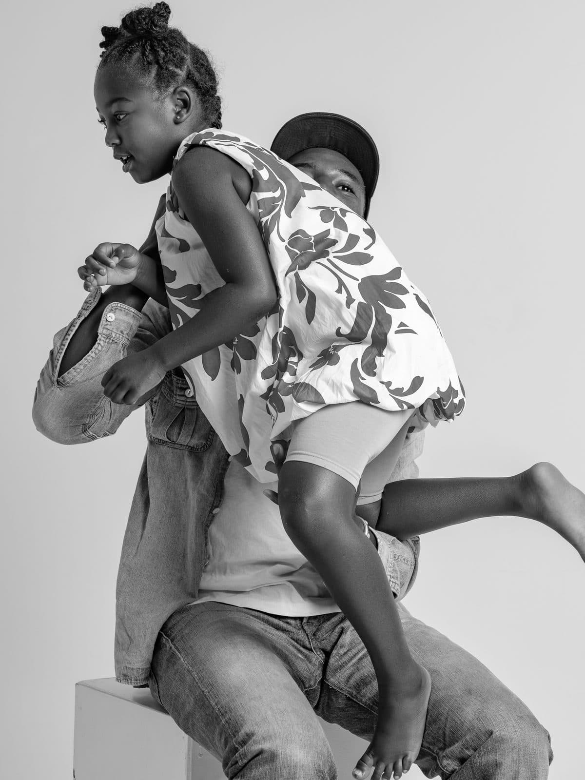 Daughter climbing on her father's shoulders