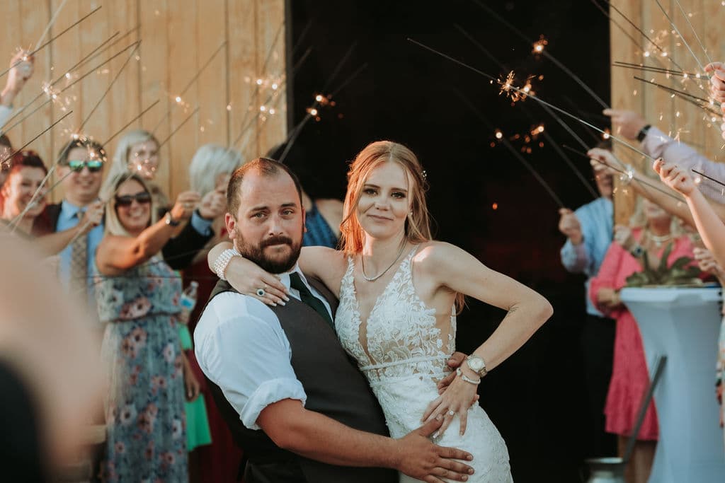Newlywed couple making a sparkler exit in front of a barn
