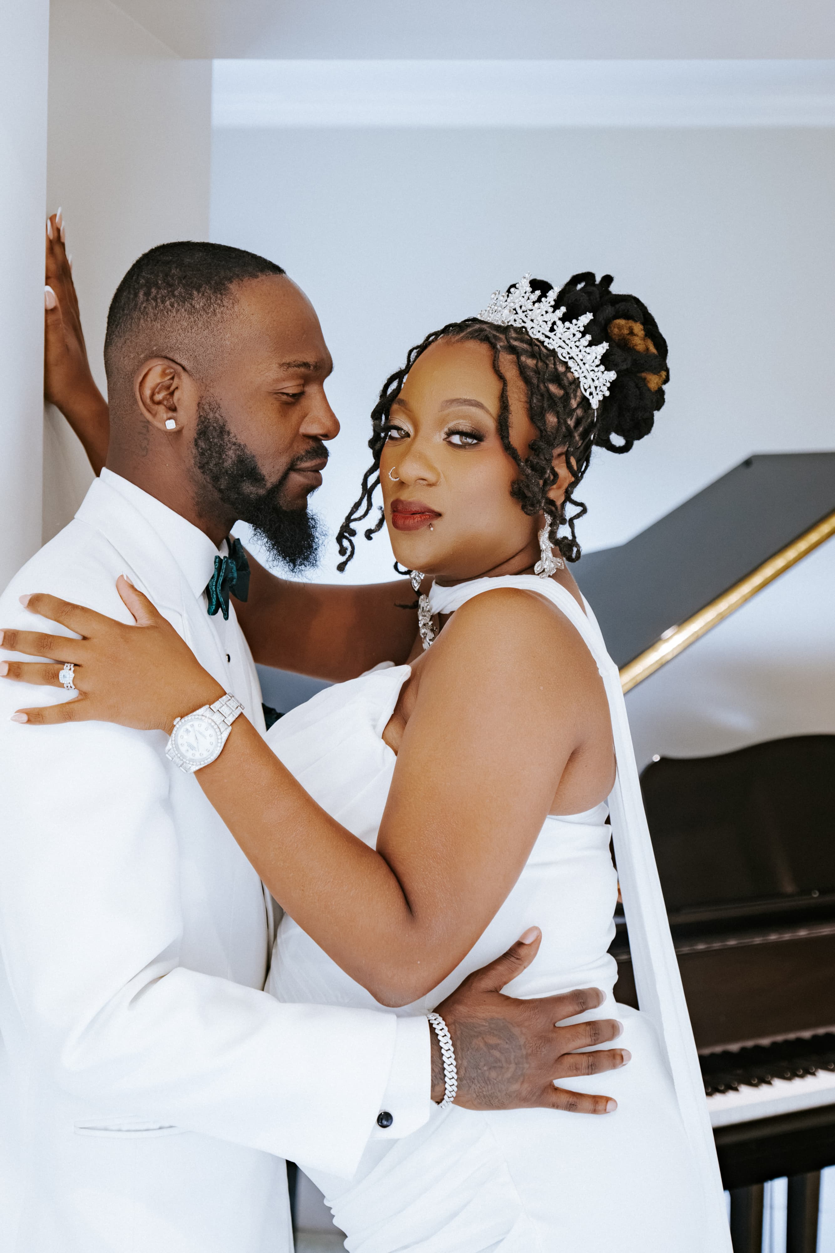 Couple in white embracing beside a grand piano on their elopement day