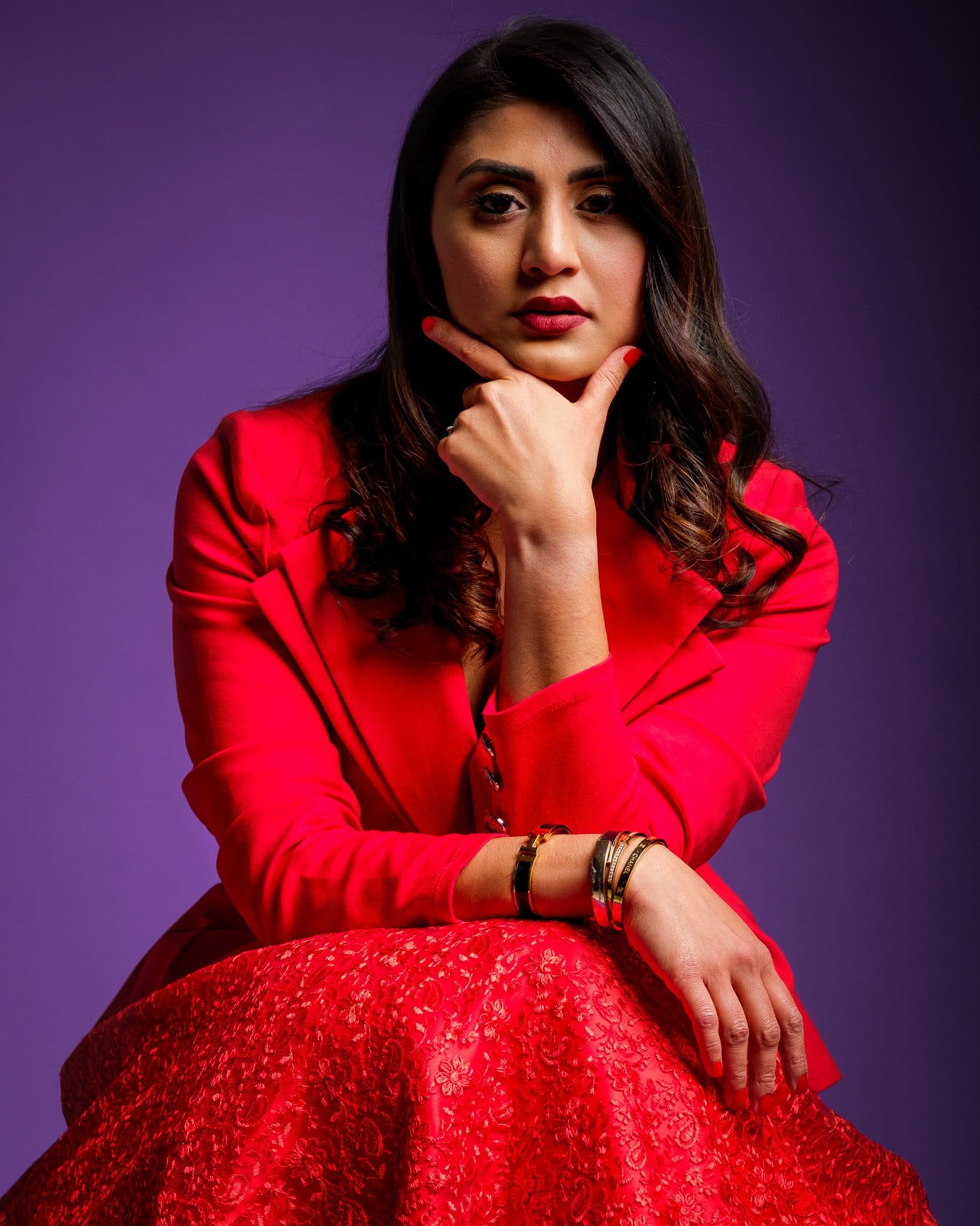 Branding portrait of a woman in a red suit against a purple backdrop