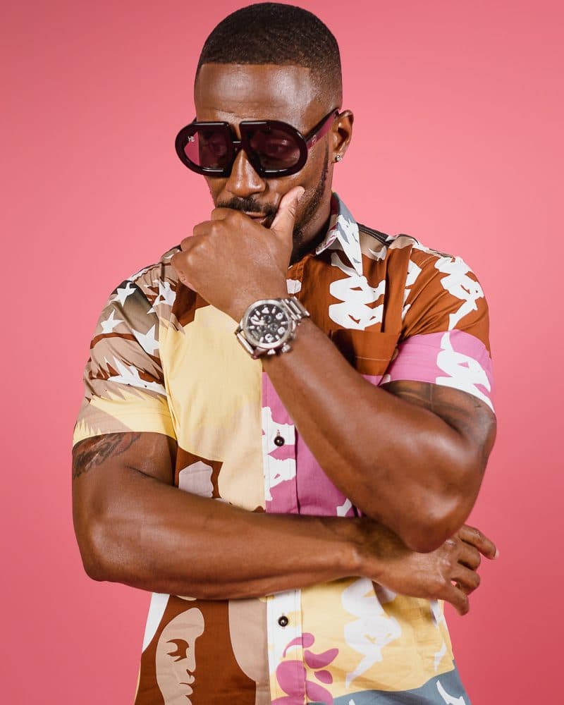 Branding portrait of a man wearing sunglasses against a pink backdrop
