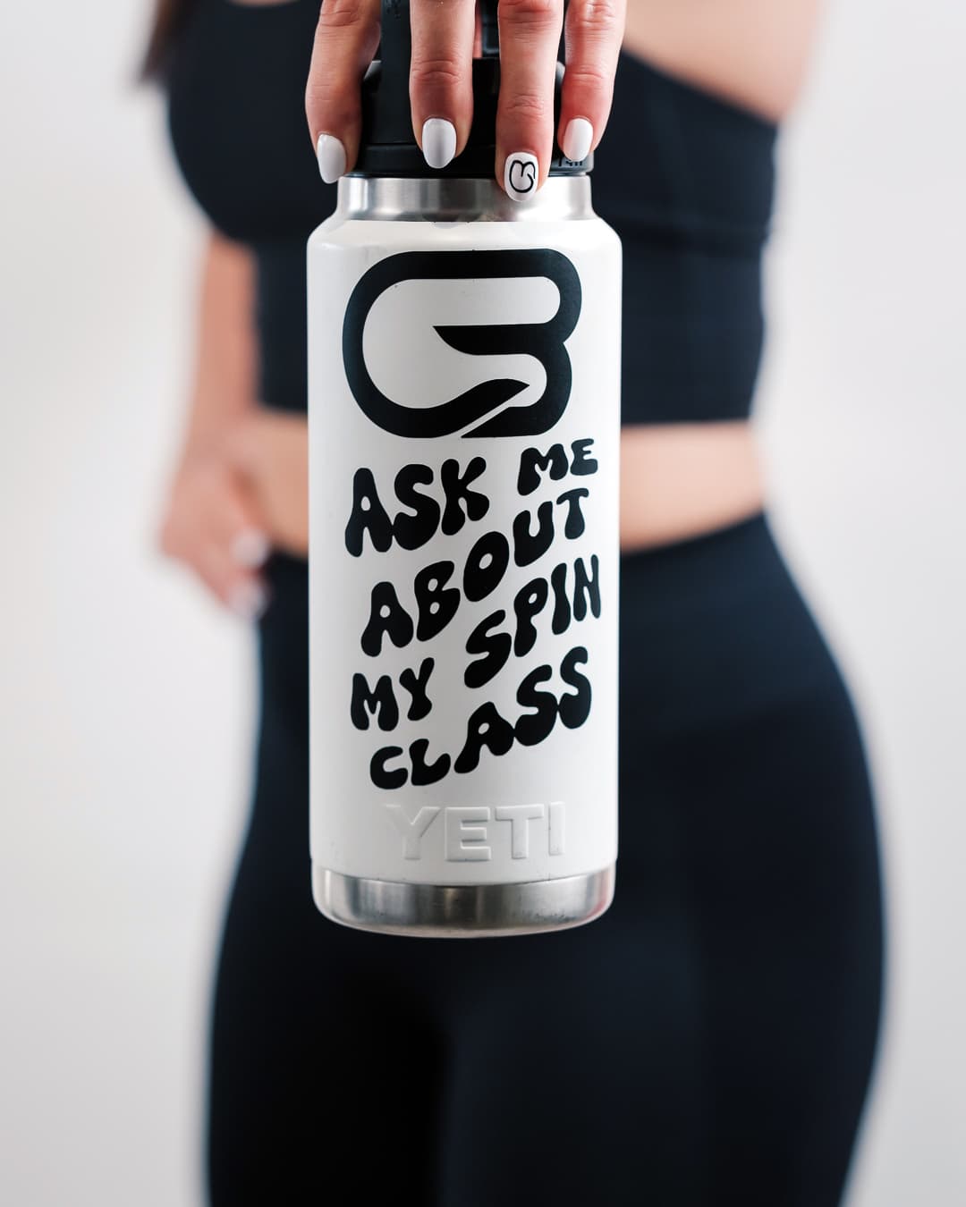 White Spin Class water bottle with bold black lettering held in front of an athlete