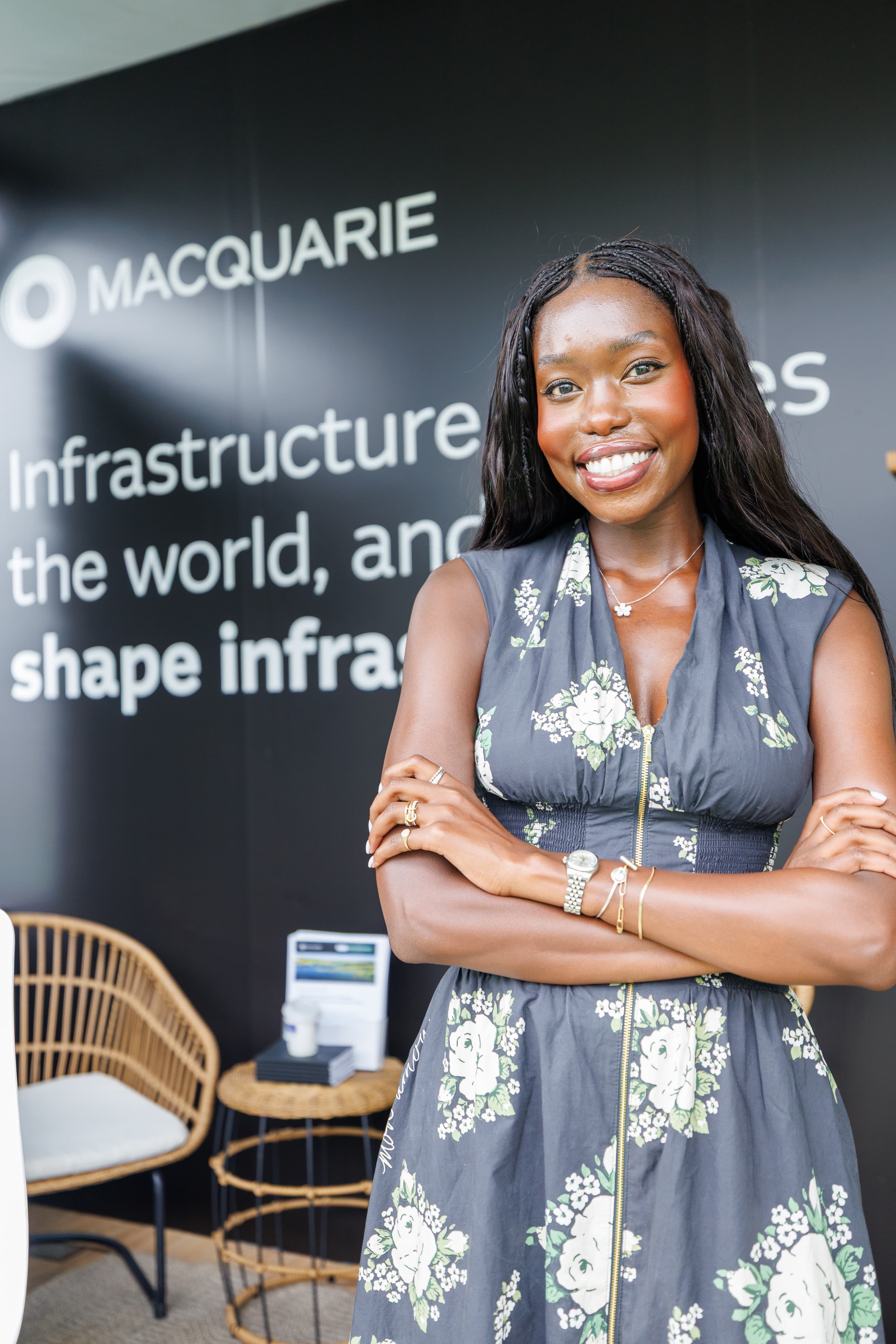 Woman in a floral dress posing with folded arms in front of a Macquarie sponsor wall