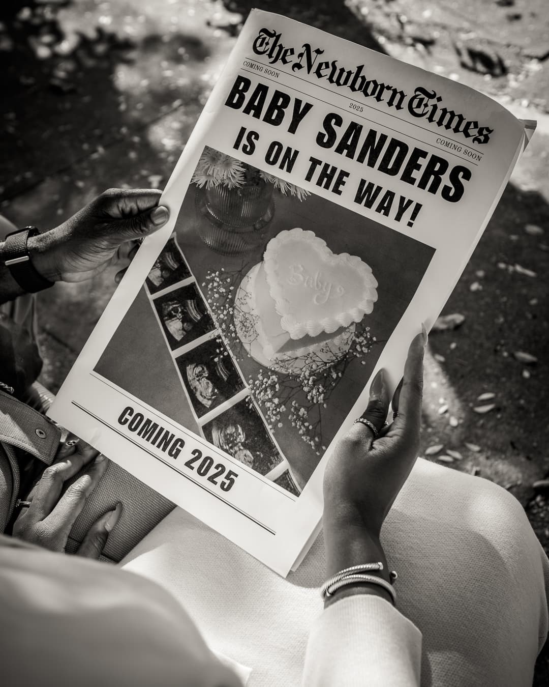 Black-and-white Baby Sanders Is On The Way newspaper announcement held outdoors