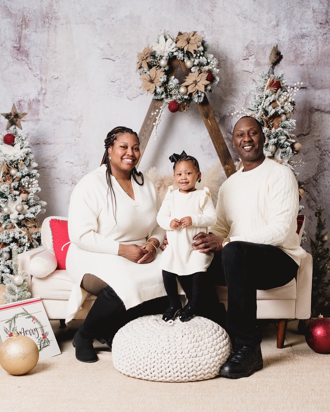 Family portrait in cream sweaters in a holiday studio setting